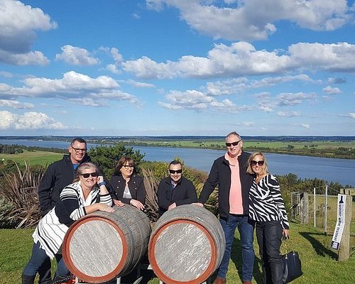 Wine tour group posing with barrels overlooking the river